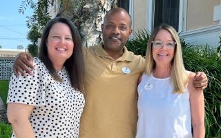 Three Tampa Y staff members pose outdoors after their promotions. One woman, one man, another woman.