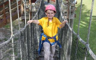 Child on ropes course heading towards zip line.