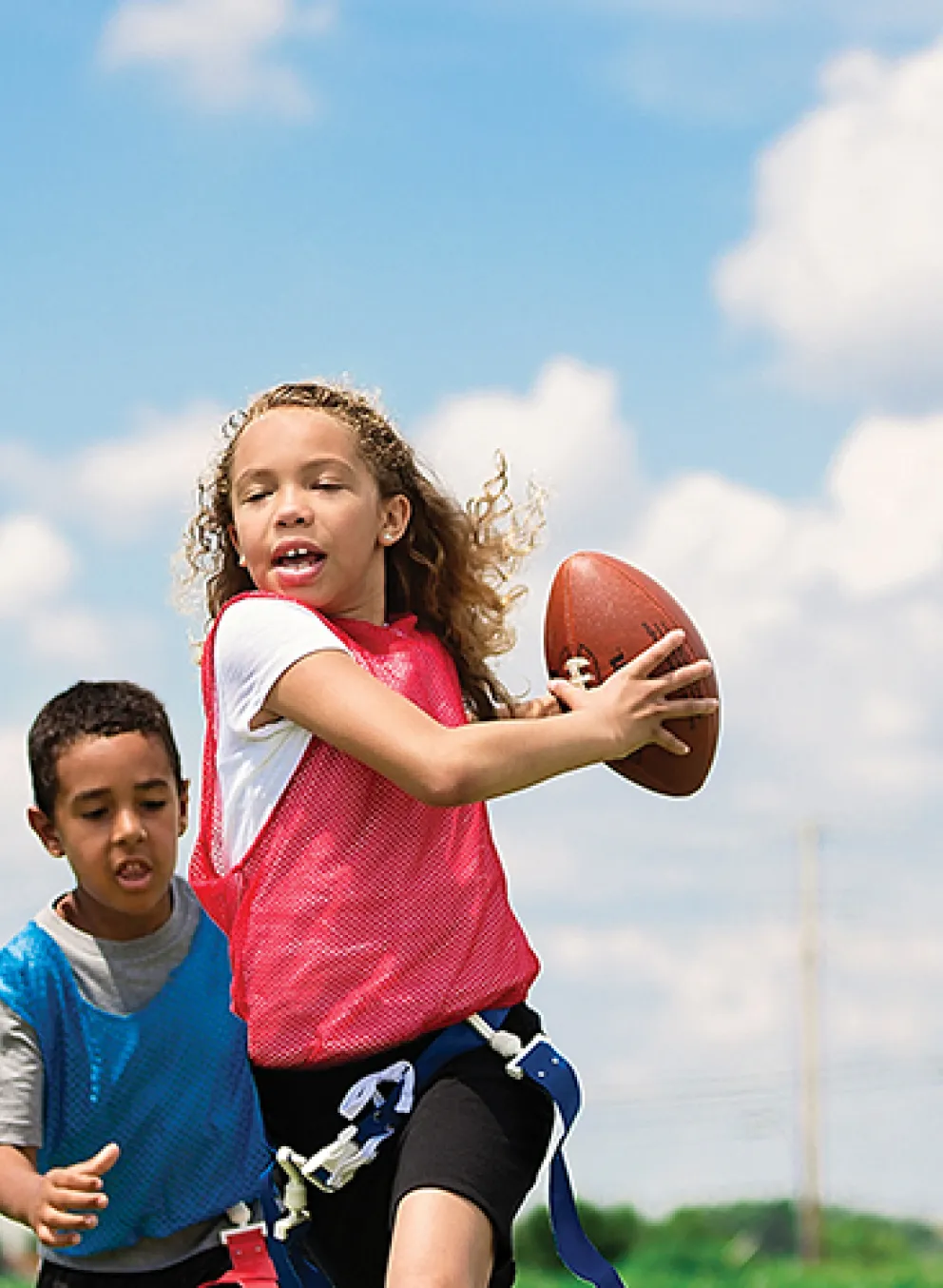 four kids playing flag football outside