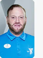 headshot of male personal trainer wearing blue YMCA polo gray background