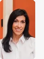 headshot of female life coach wearing white button down orange background