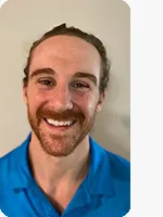 headshot of male personal trainer wearing blue YMCA polo gray background