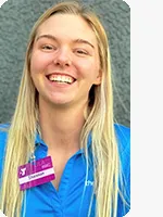 headshot of female personal trainer wearing blue YMCA polo gray background